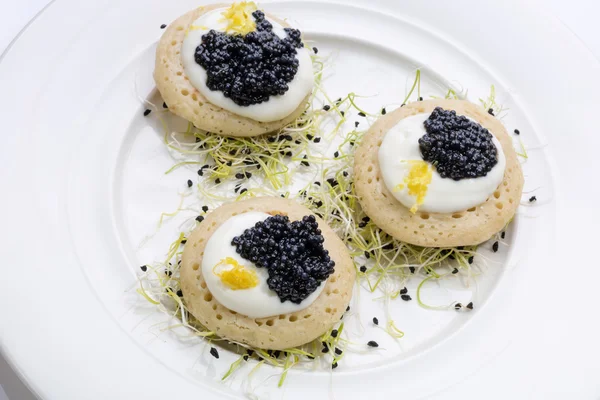 Krep krema ve pırasa lahanası bir yatak üzerinde kızarmış balık havyar. Beyaz tabakta yemek. metin için yer.