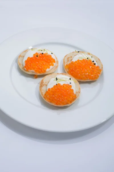 Caviar de pescado rojo en panqueques con crema. comida en un plato blanco. espacio para texto . — Foto de Stock