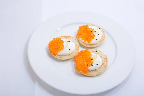 Red fish caviar on pancakes with cream. food on a white plate. space for text. — Stock Photo, Image