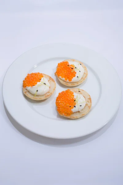 Roter Fischkaviar auf Pfannkuchen mit Sahne. Essen auf einem weißen Teller. Raum für Text. — Stockfoto