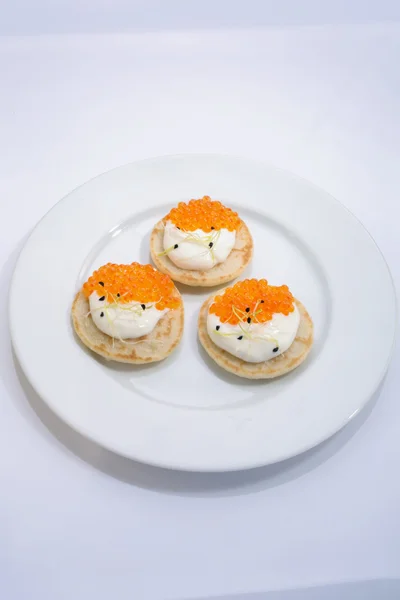 Roter Fischkaviar auf Pfannkuchen mit Sahne. Essen auf einem weißen Teller. Raum für Text. — Stockfoto