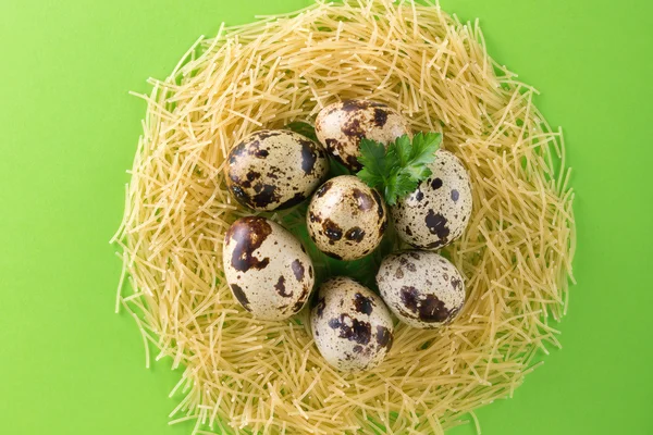 緑の背景に生パスタ麺の巣の形でクッションにウズラの卵。明るい背景上水平フラット オブジェクト。パスタ イタリア料理 — ストック写真