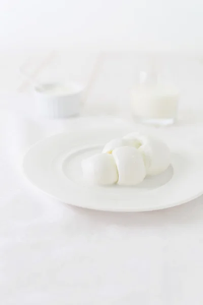 Trozo de queso en forma de trenzas en un plato blanco. Foto del producto lácteo en una tecla de luz. naturaleza muerta en blanco. Producto italiano tradicional —  Fotos de Stock