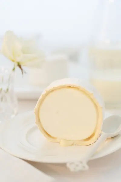 Egy darab kecskesajt egy fehér lemezre. Élelmiszer nagy klyuche.frantsuzskie sajtok a lövés. fehér fehér csendélet — Stock Fotó