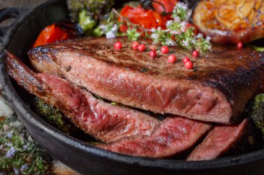 Sığır eti biftek pişmiş sebzeler bir dökme demir tava üzerinde. düşük anahtar yiyecek natürmort. bir fincan Avrupa mutfağı. rustik tarzda gıda