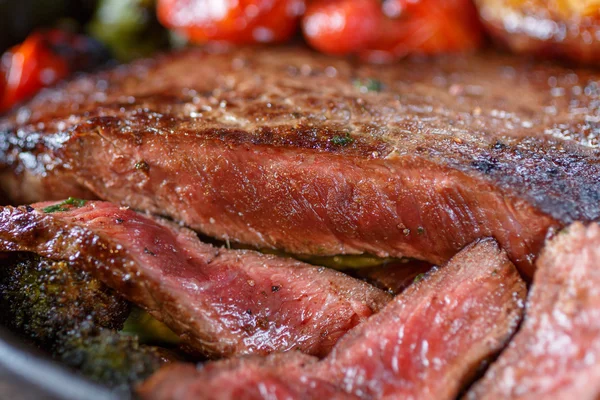 Rundvlees biefstuk medium zeldzame met groenten op een gietijzeren koekepan. Stilleven van voedsel in lage sleutel. een gerecht van de Europese keuken. voedsel in rustieke stijl — Stockfoto