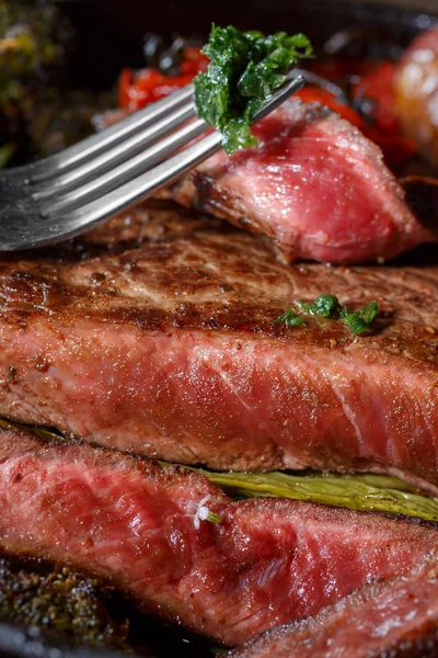 Rundvlees steak middelgrote zeldzame stukken met een garnituur van groenten in een gietijzeren koekepan. het vlees wordt doodgeschoten in lage sleutel. vette voedingsmiddelen rijk aan eiwitten. klaar vleesgerecht in rustieke stijl — Stockfoto
