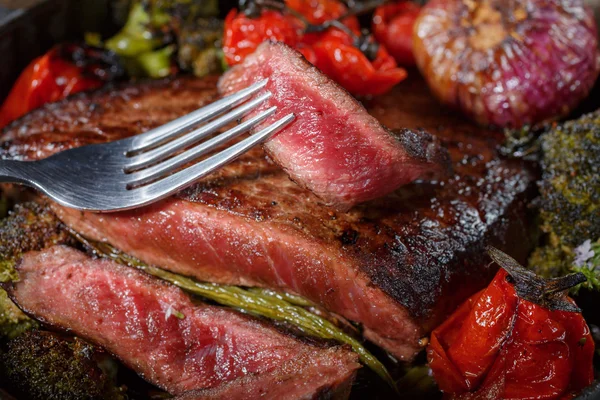 Rundvlees steak middelgrote zeldzame stukken met een garnituur van groenten in een gietijzeren koekepan. het vlees wordt doodgeschoten in lage sleutel. vette voedingsmiddelen rijk aan eiwitten. klaar vleesgerecht in rustieke stijl — Stockfoto
