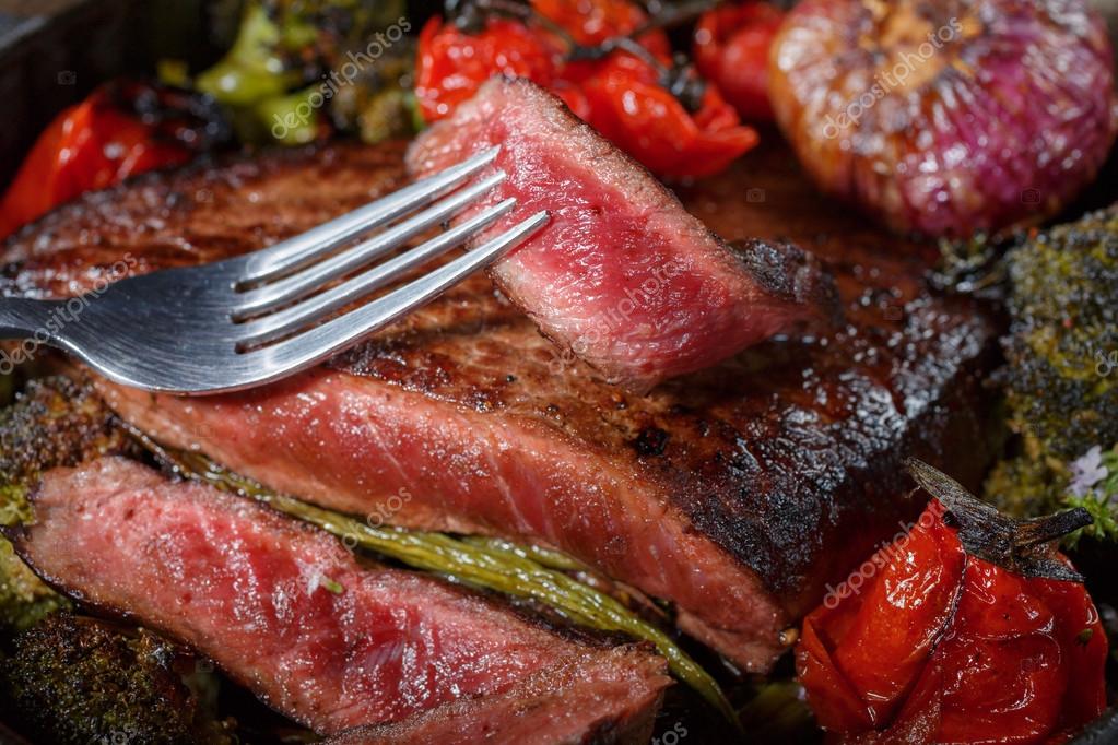Beef steak medium rare pieces with a garnish of vegetables in a cast