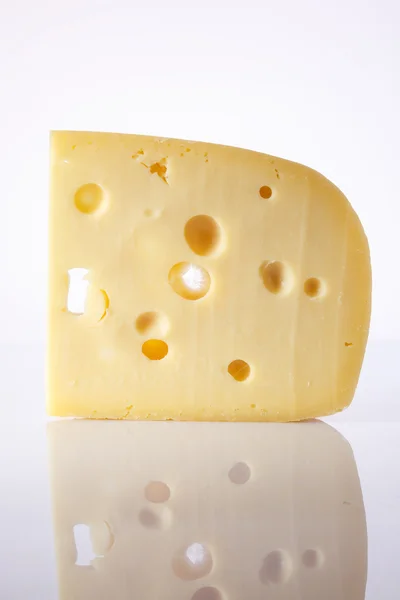 Mjölkprodukt. bit ost med stora holes.a bit ost med stora hålen på ljus bakgrund med en toning. alpinland. — Stockfoto