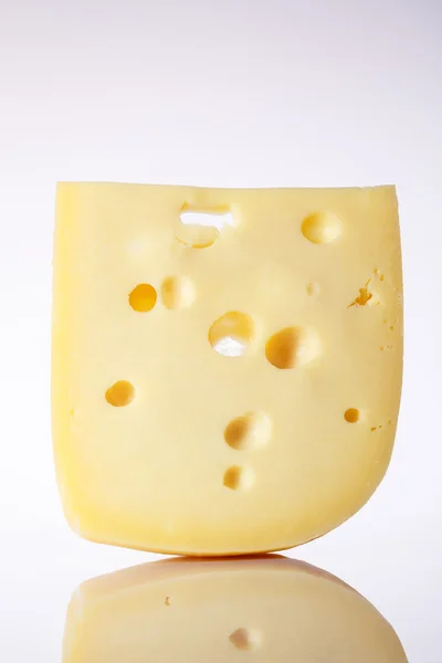 Produits laitiers. morceau de fromage avec de grands trous.un morceau de fromage avec les grands trous sur un fond clair avec un gradient. alpinland . — Photo