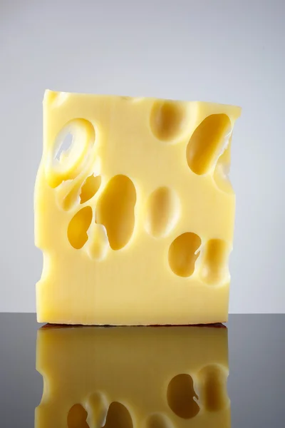 En bit ost med stora hålen på ljus bakgrund med en toning. Emmentaler. — Stockfoto