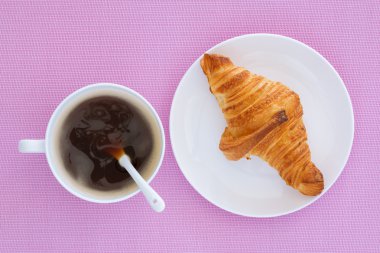 kruvasan bir beyaz plaka ve pembe bir arka plan üzerinde