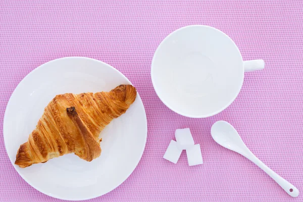 Croissant auf weißem Teller und rosa Hintergrund — Stockfoto