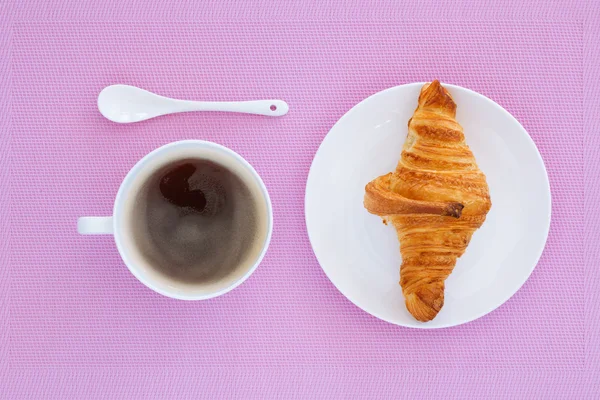 Croissant auf weißem Teller und rosa Hintergrund — Stockfoto