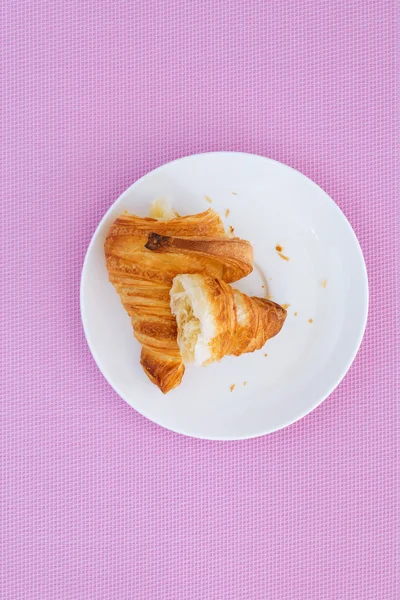 Croissant on a white plate and pink background — Stock Photo, Image