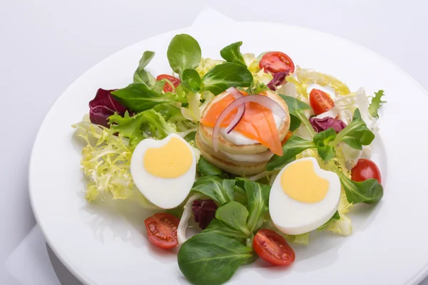 La ensalada verde con los huevos en forma del corazón, el salmón, los tomates de guinda — Foto de Stock