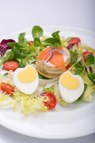 La ensalada verde con los huevos en forma del corazón, el salmón, los tomates de guinda —  Fotos de Stock