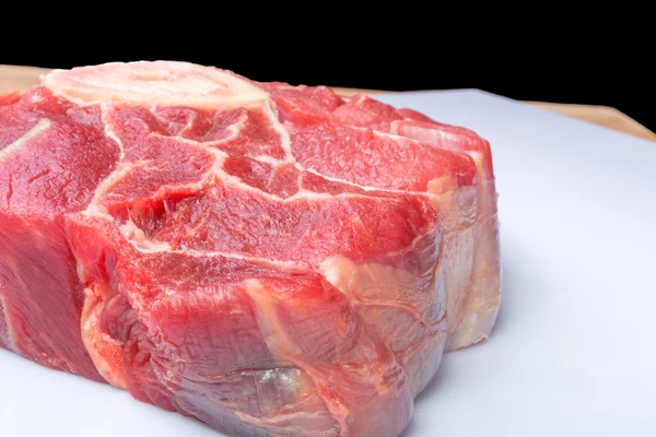Um pedaço de carne crua ossobuco em um fundo preto — Fotografia de Stock