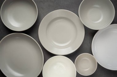 white round empty plates and bowls on dark background