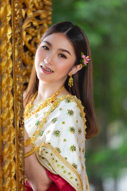 beautiful woman in thai traditional outfit smiling and standing at temple 