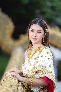 beautiful woman in thai traditional outfit smiling and standing at temple 