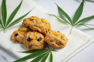 cannabis cookies and cannabis leaves put on white napkin