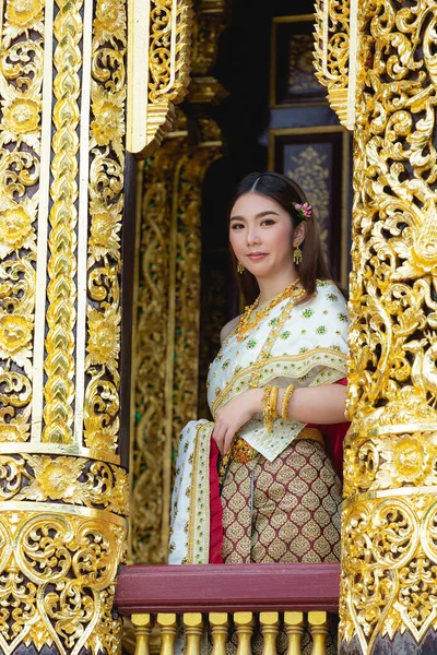 beautiful woman in thai traditional outfit smiling and standing at temple