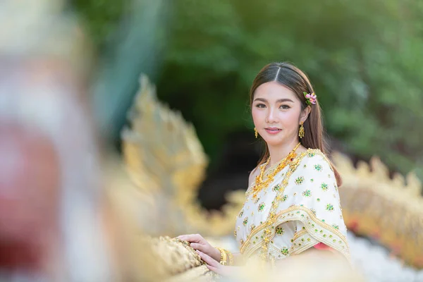 beautiful woman in thai traditional outfit smiling and standing at temple
