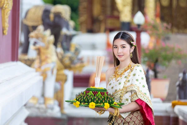 beautiful woman in thai traditional outfit smiling and standing at temple