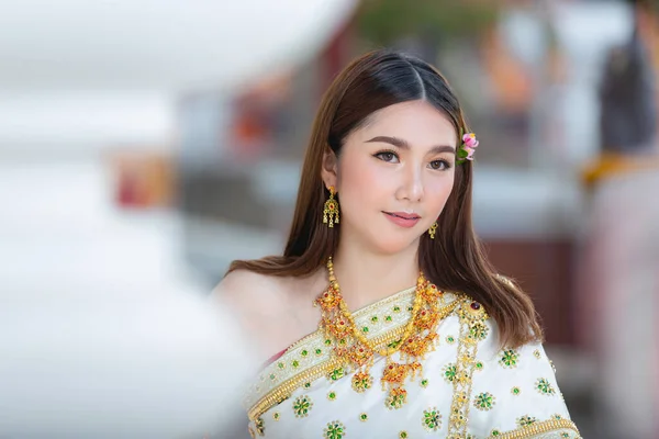 beautiful woman in thai traditional outfit smiling and standing at temple