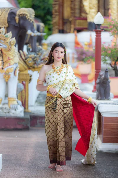 beautiful woman in thai traditional outfit smiling and standing at temple