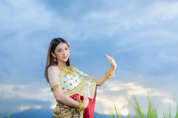 beautiful woman in thai traditional outfit smiling and standing at temple