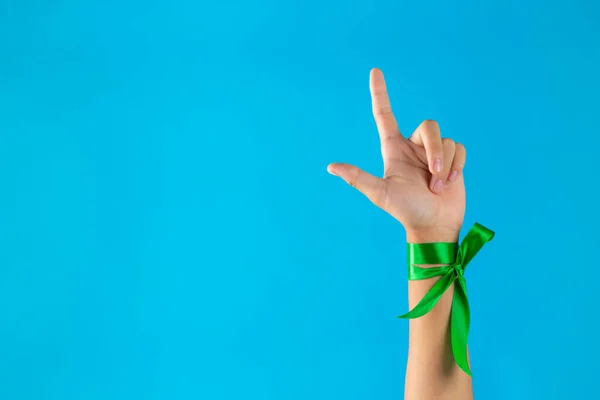 World Mental Health Day;green ribbons tied at the wrist on blue background