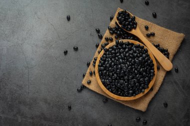 Siyah fasulye küçük ahşap bir tabak içinde çuval kumaşın üzerinde