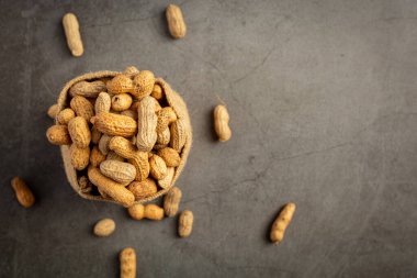 Bir çuval yerfıstığı koyu arkaplana konmuş.