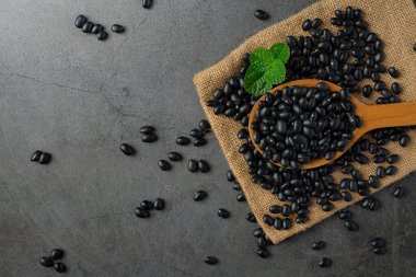 Siyah fasulye küçük tahta kaşık içinde çuval kumaşın üzerinde