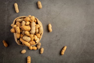 Bir çuval yerfıstığı koyu arkaplana konmuş.