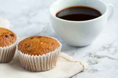 Çikolatalı kekler ve beyaz mermer zeminde bir fincan kahve.