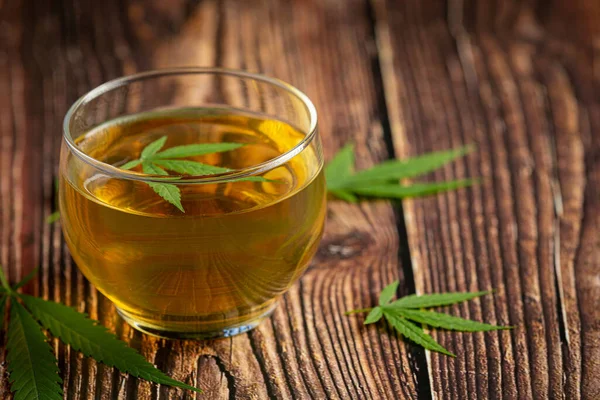 a glass of hemp tea with hemp leaves put on wooden floor