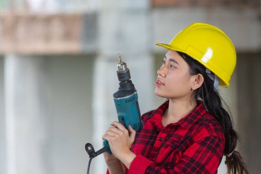 İnşaat alanında elektrikli matkap tutan işçiler, İşçi Bayramı konsepti