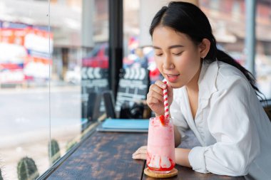Genç Asyalı kadınlar kafede çilekli smoothie içerler.