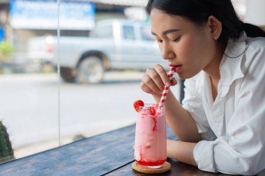 Genç Asyalı kadınlar kafede çilekli smoothie içerler.
