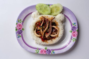 Üzerine kızarmış kalamar ve beyaz arka planda fesleğen konmuş pirinç.