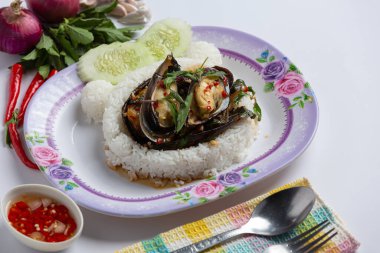 Üzerine kızarmış midye ve beyaz arka planda fesleğen konmuş pirinç.