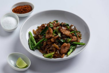 Soya soslu kızarmış pirinç eriştesi ve beyaz arka planda domuz eti.