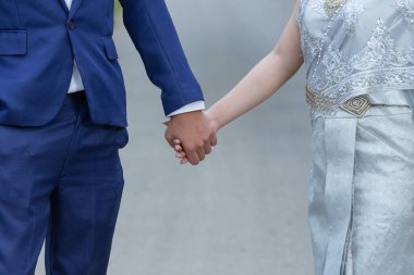 Genç bir kadın, çiçek bahçesinde yol gösterirken erkeğin elini tutuyor.