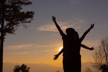 Genç çift dağda günbatımının tadını çıkarıyor.