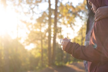 Sabahları parkta kahve içen mutlu kadın.