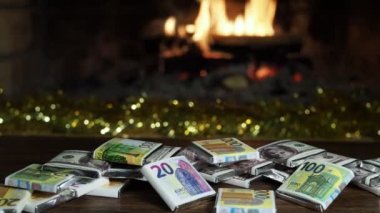 Tatil sezonu, dekorasyonlar. Ambalajlı çikolatalar şömine ateşinin arka planına karşı banknot olarak şekillendirildi. Yakın çekim..